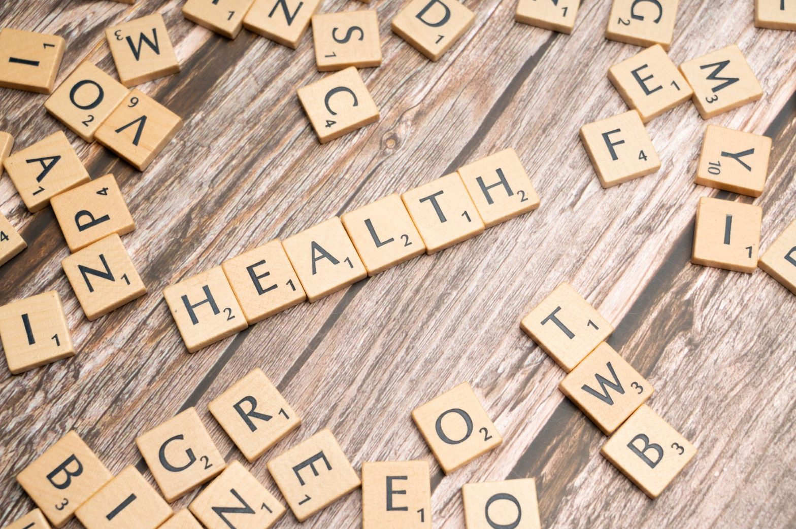 Scrabble tiles spelling 'HEALTH' on wooden surface, symbolizing wellness. — Inside the Mind of Dr. James Morales: Optimizing