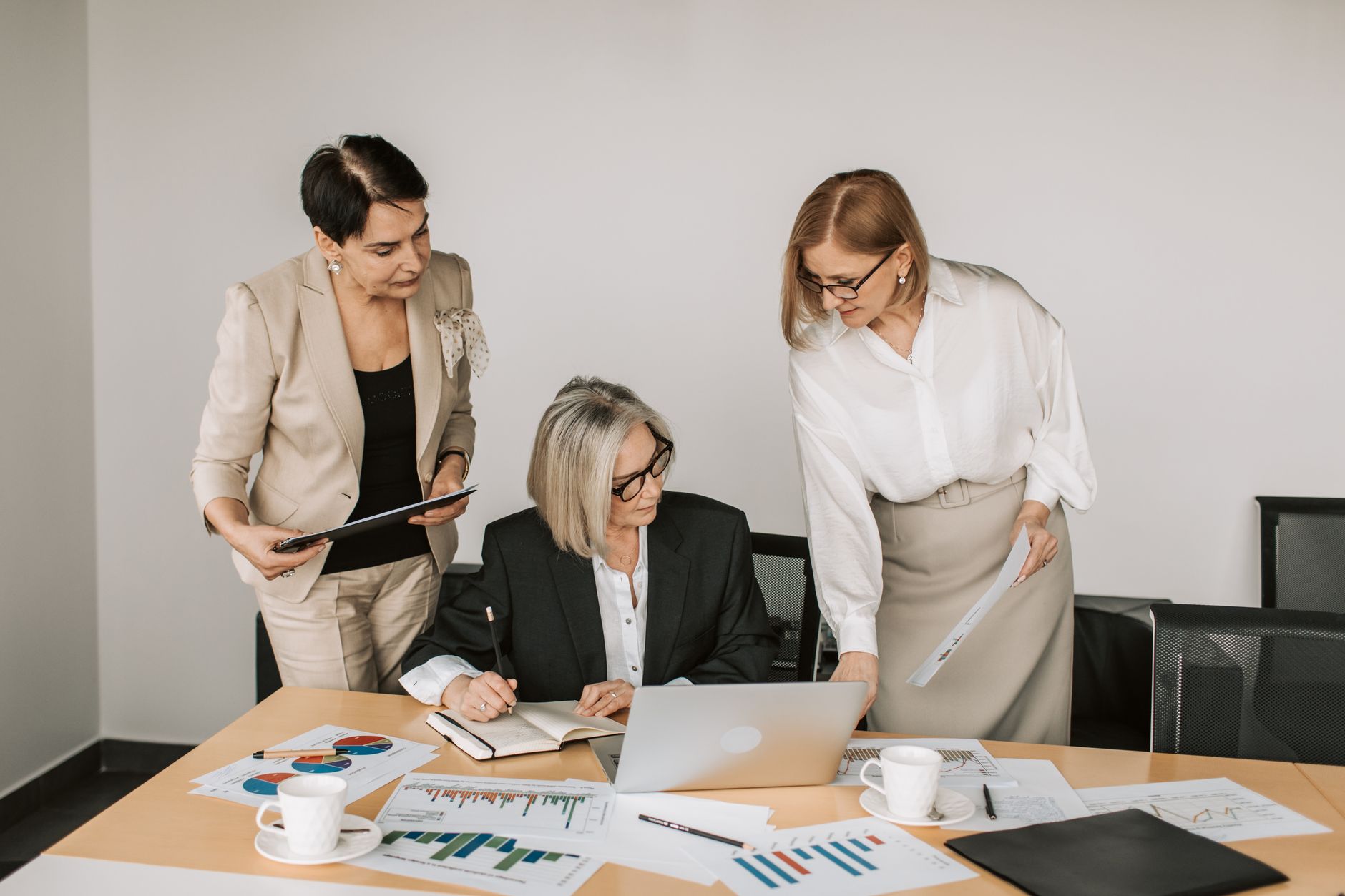 Three businesswomen discussing documents during a meeting in a modern office setting. — Navigating Testosterone Pricing: Fact