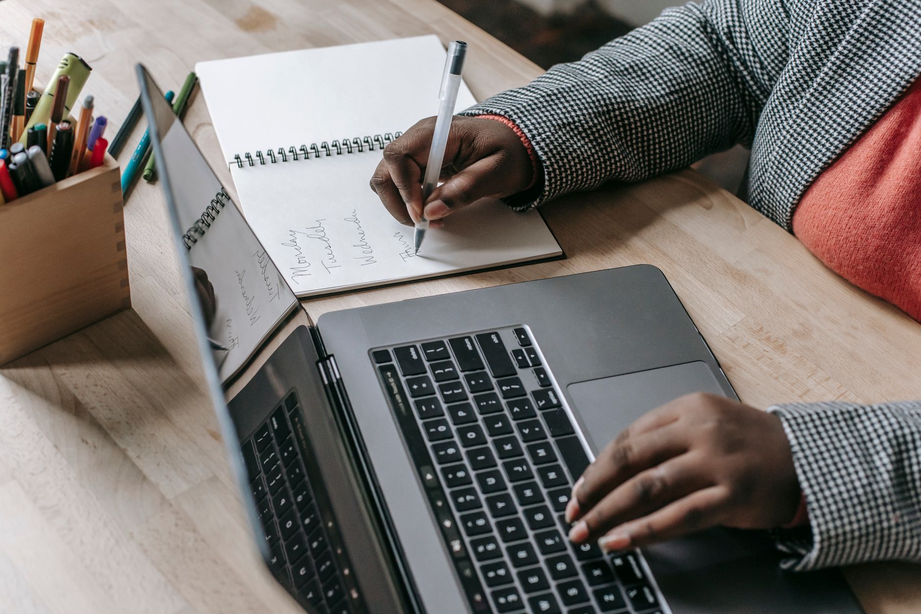 Crop unrecognizable African American female in formal wear writing notes in notepad while working on laptop — Praktyczne zast